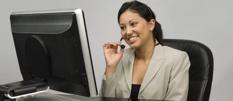 Financial Aid representative looking at a computer and wearing a headset.